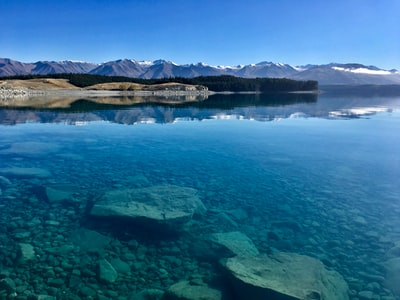 白天水体旁的棕色和白色山脉